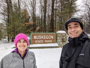 woman and man at entrance sign for Muskegon State Park
