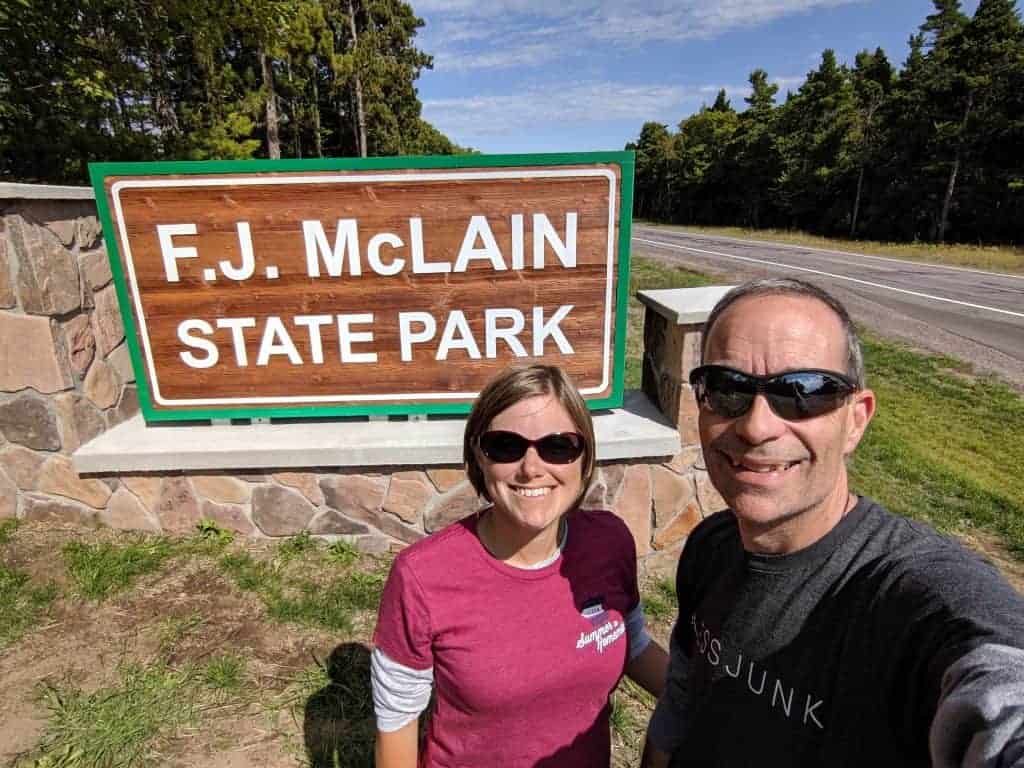 A man and woman in front of the McLain State Park entrance sign