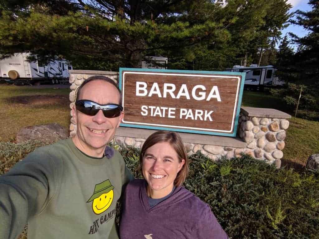 An adult male and female standing in front of a state park sign