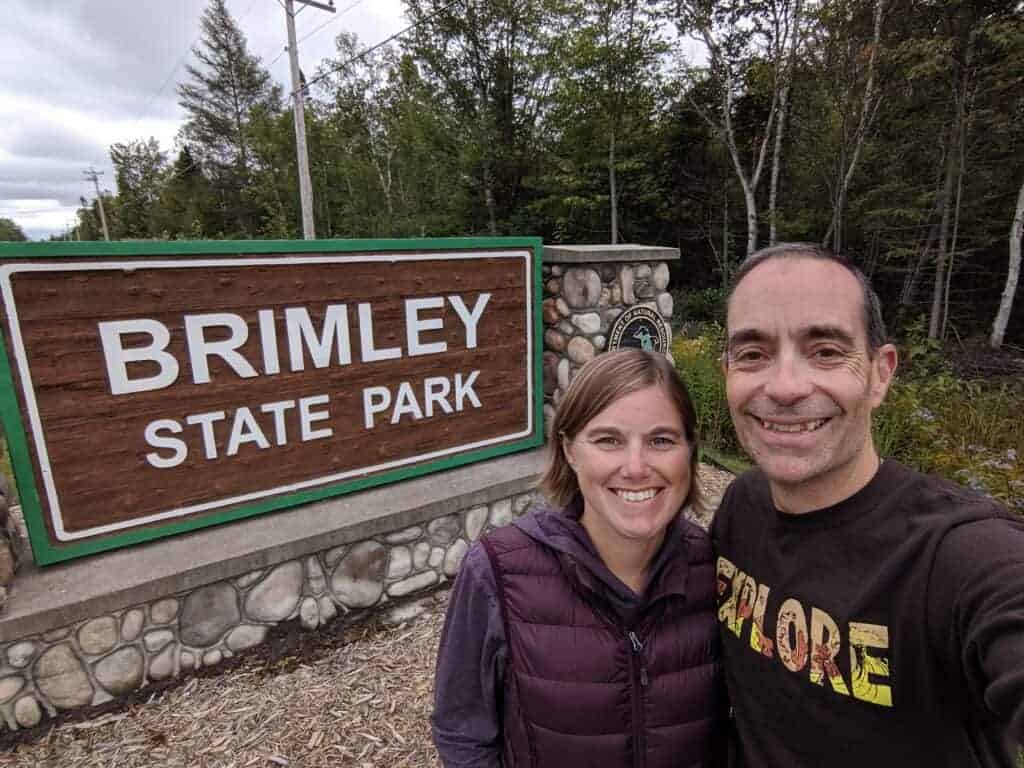 Two adults in front of the entrance sign at Brimley State Park