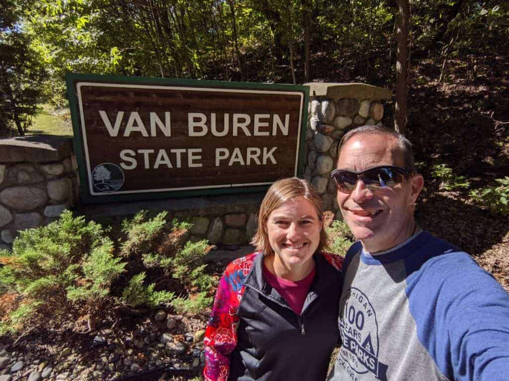 A man and woman in front of a state park entrance sign