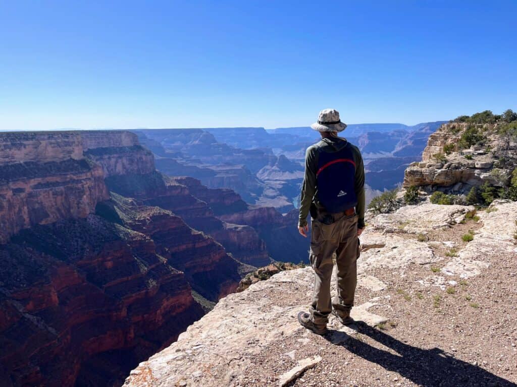 Stunning view of the Grand Canyon at sunrise with a hiker enjoying the scenic overlook and exploring the natural landscape.