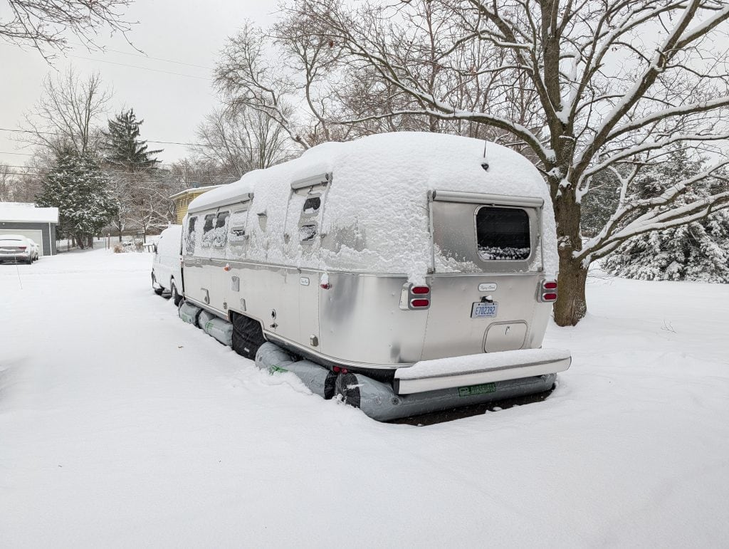 An RV covered in snow during winter, demonstrating the importance of winter protection with Xtreme Heaters and AirSkirts for safe and efficient cold-weather camping.