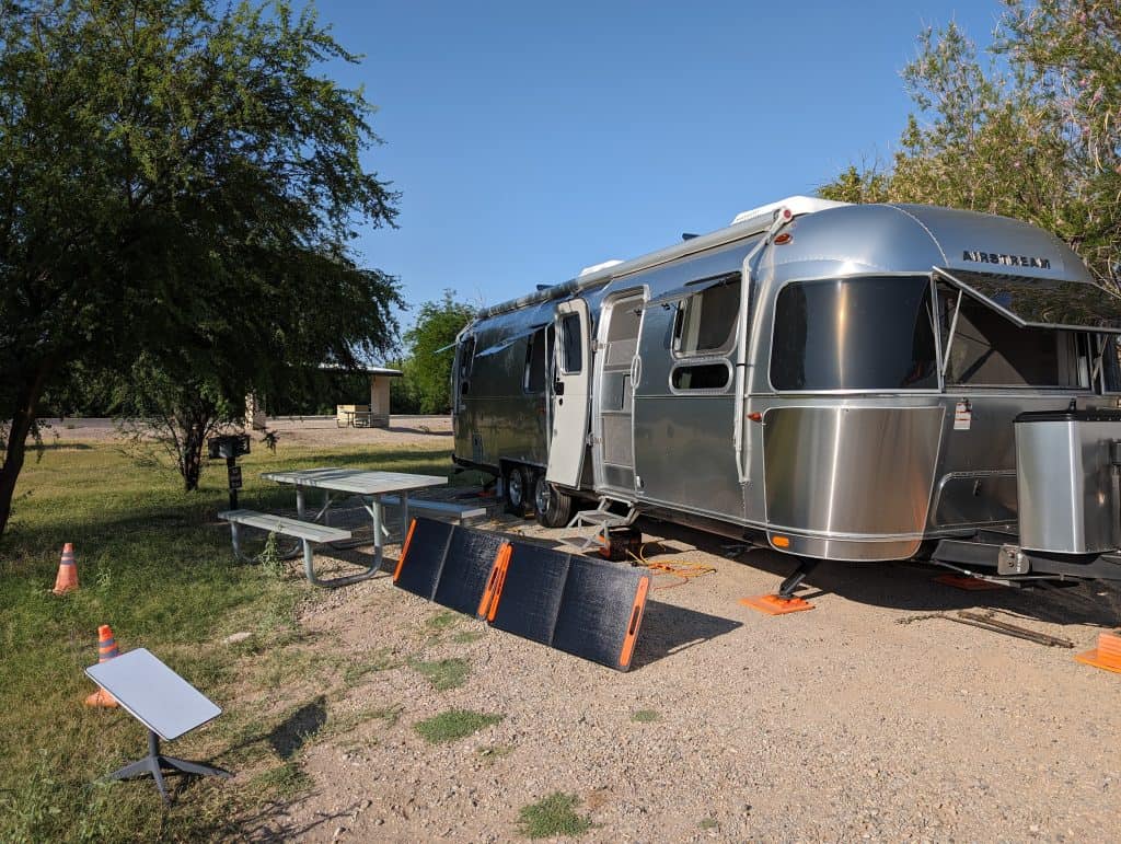 Airstream trailer with solar panels parked outdoors, highlighting sustainable home options and reducing carbon footprint.